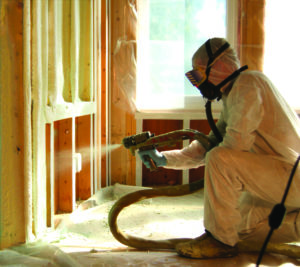Technician applying spray foam to an interior wall.