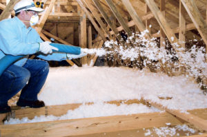 insulation installer blowing fiberglass insulation in attic