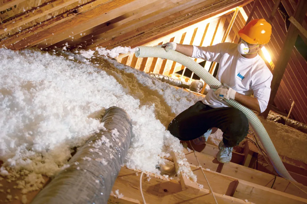 IBP employee blowing fiberglass insulation in attic